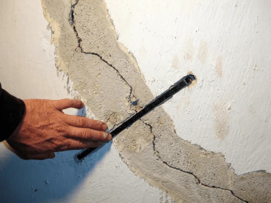 A wall with a large crack is being inspected by a professional in Chattanooga, TN